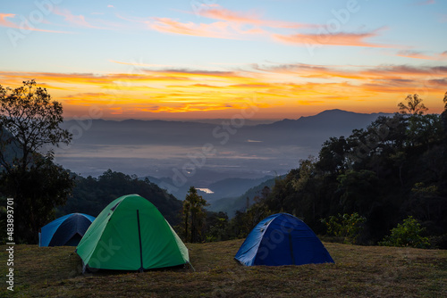 Vivid tents with awesome view to high mountain range under first light of sun in sunrise sky. Scenic landscape with tent at very high altitude with view to large mountains.