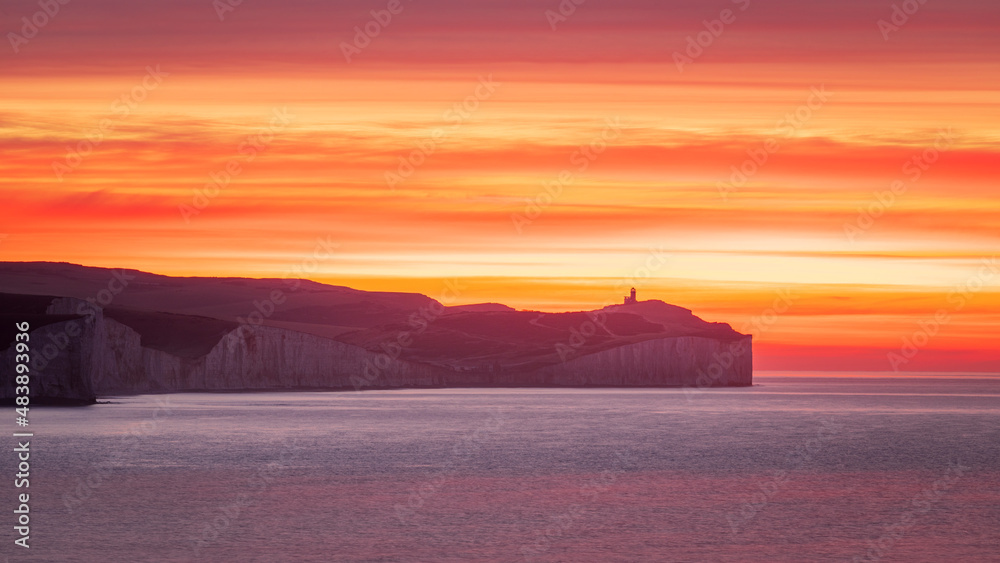 Colourful January sunrise from the cliff edge of Seaford Head looking out towards the Seven Sisters and Belle Tout lighthouse on the east Sussex coast, south east England