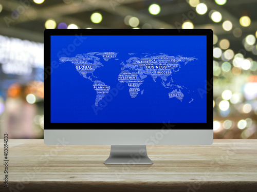 Global business words world map on desktop modern computer monitor screen on wooden table over blur light and shadow of shopping mall  Global business online concept  Elements of this image furnished 