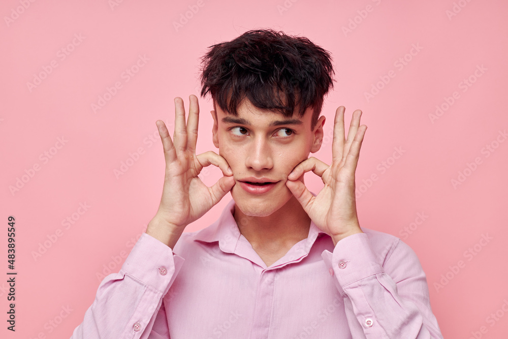 A young man gestures with hands emotions hairstyle fashion pink background unaltered A young man gestures with hands emotions hairstyle fashion pink background unaltered