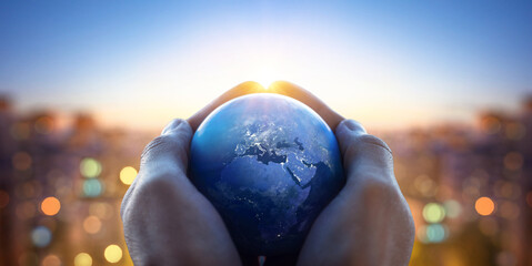 Earth in hands of a man against the background of lights of the evening city. Concept and symbol on theme of ecology, earth conservation, news and religion. Elements of this image furnished by NASA.