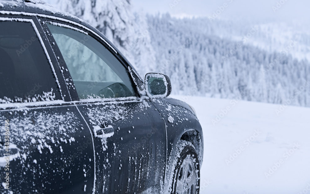 Fototapeta premium Frozen car and covered with snow and ice parked in a parking lot on top of a mountain resort