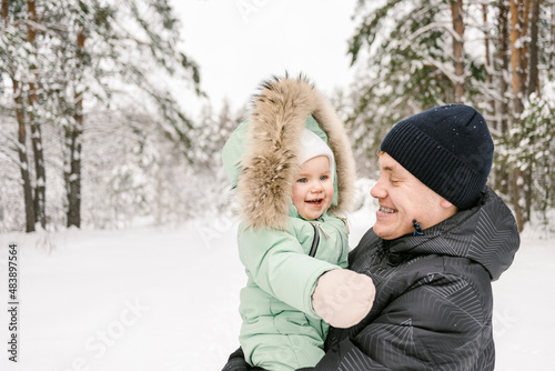 Happy father carrying cute daughter wearing parka jacket in winter photo