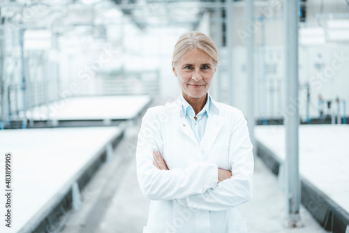 Confident biologist with arms crossed standing in laboratory photo