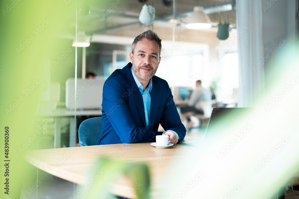 Businessman sitting with coffee cup at desk in workplace Businessman sitting with coffee cup at desk in workplace