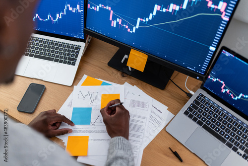 Young trader making strategy on paper working late night at home office