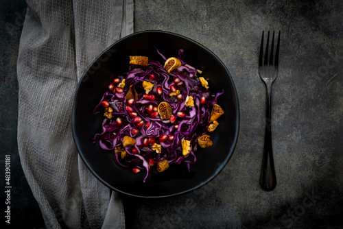 Studio shot of bowl of vegan salad with red cabbage, pomegranate seeds, dried figs and walnuts photo