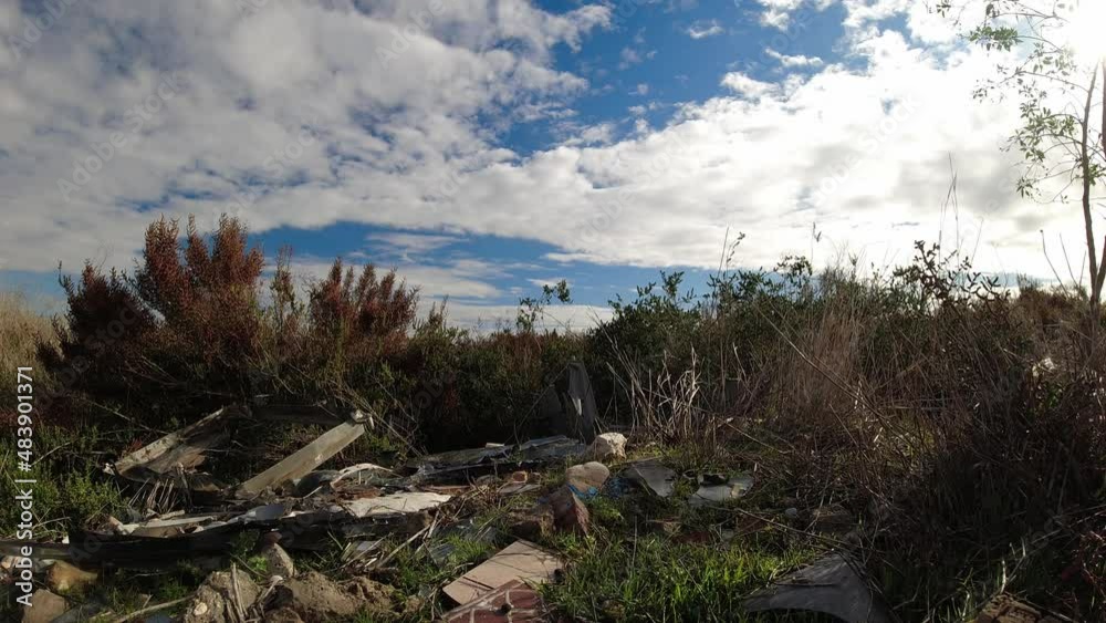 A pile of trash on the ground polluting the environment in an otherwise beautiful environment - cloudscape time lapse A pile of trash on the ground polluting the environment in an otherwise beautiful environment - cloudscape time lapse