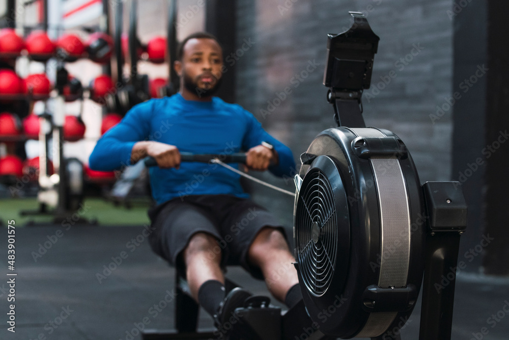 Athlete exercising on rowing machine in gym Athlete exercising on rowing machine in gym