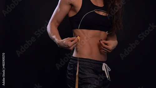 A beautiful girl with a sporty figure, measuring her waist. Body-building.