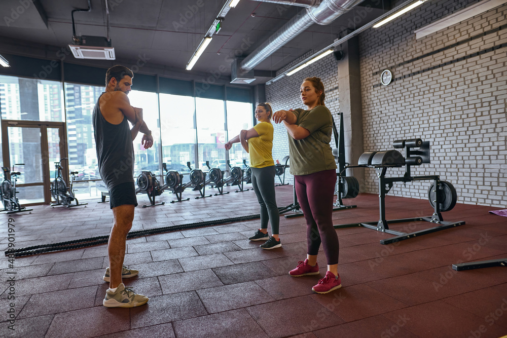 Fototapeta premium Girls and trainer stretching hands before training