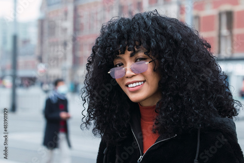 Smiling young woman with curly black hair wearing sunglasses