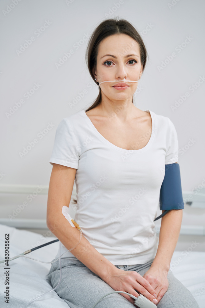 Despondent woman sitting in hospital ward during medical procedure Despondent woman sitting in hospital ward during medical procedure