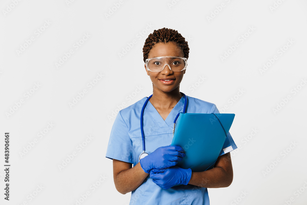 Black doctor wearing uniform smiling while posing with folder Black doctor wearing uniform smiling while posing with folder
