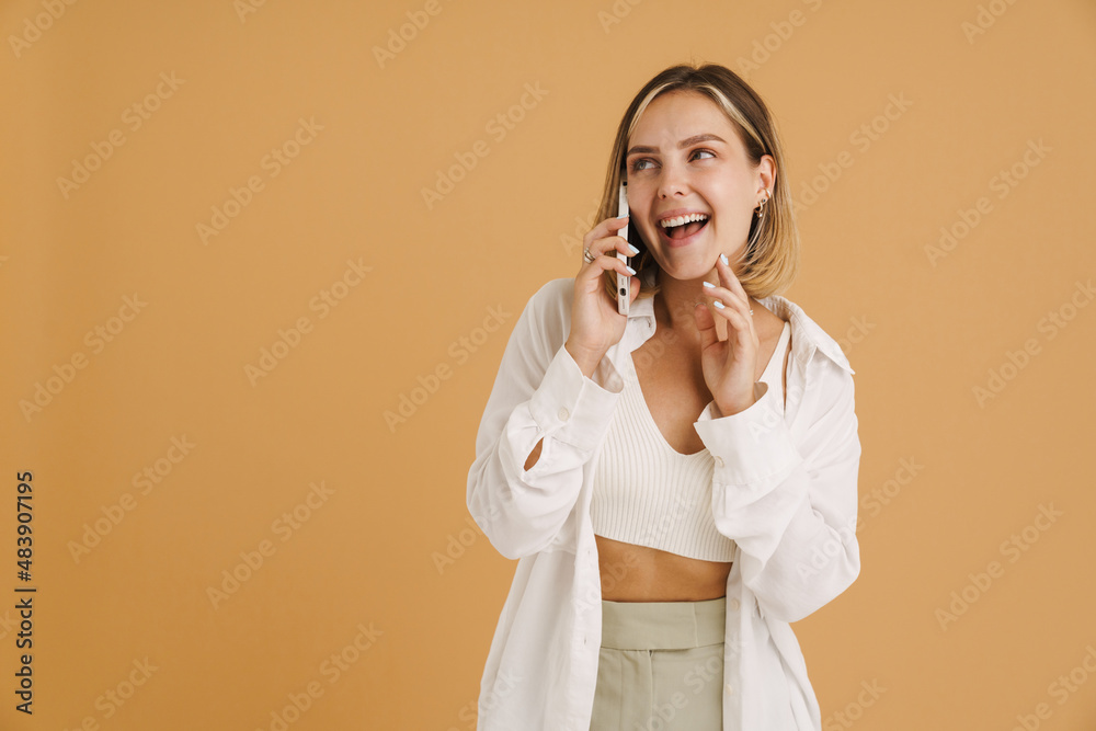 Young blonde woman smiling while talking on mobile phone