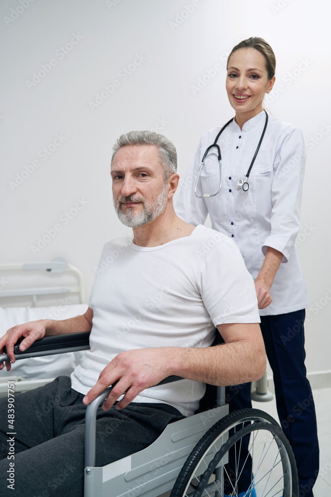 Smiling physiotherapist and her male patient posing for camera Smiling physiotherapist and her male patient posing for camera