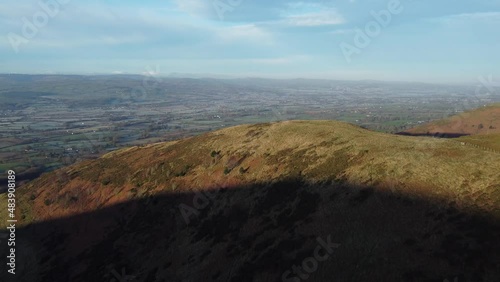 Early sunlight on highland Moel Famau mountain peak aerial rising view across vast frosty idyllic farmland countryside photo