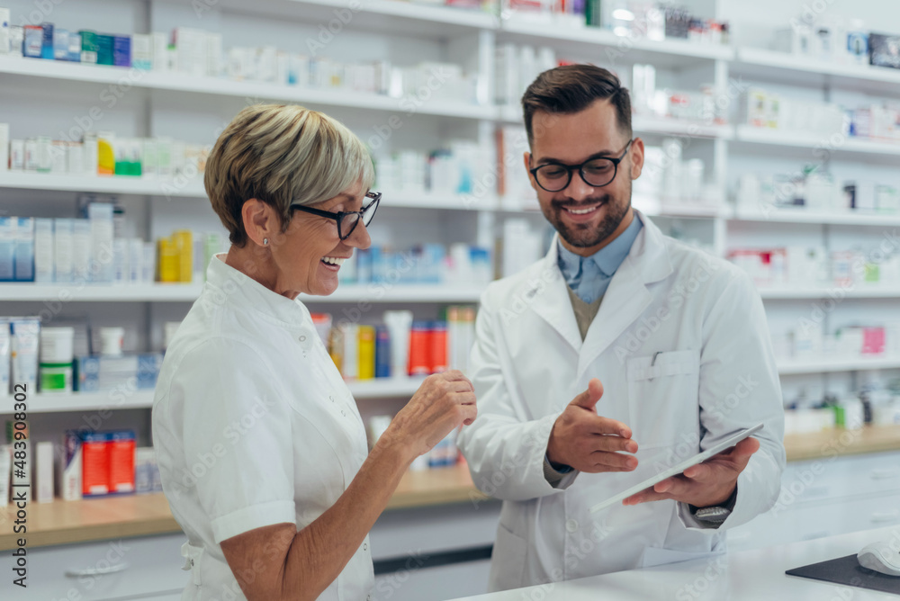 Happy young male pharmacist working with senior colleague Happy young male pharmacist working with senior colleague