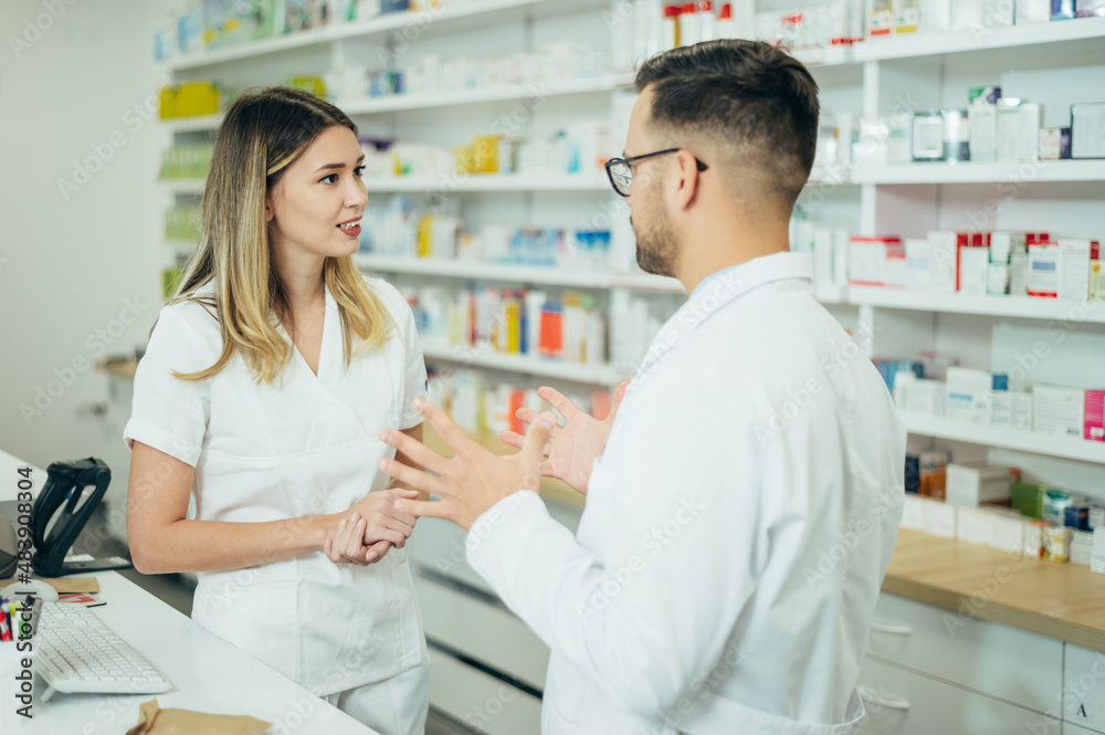 Happy young male and female colleagues pharmacist working in a pharmacy