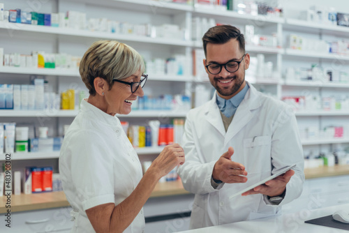 Happy young male pharmacist working with senior colleague