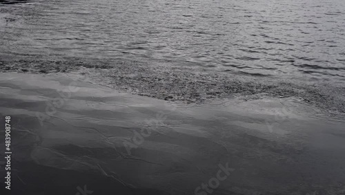 Dark Water surface with partially melted ice in wind with reflections. Climate change.