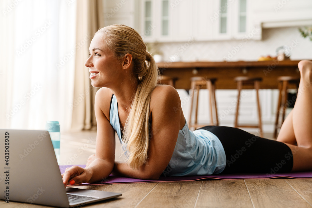 Blonde woman using laptop during yoga practice at home Blonde woman using laptop during yoga practice at home
