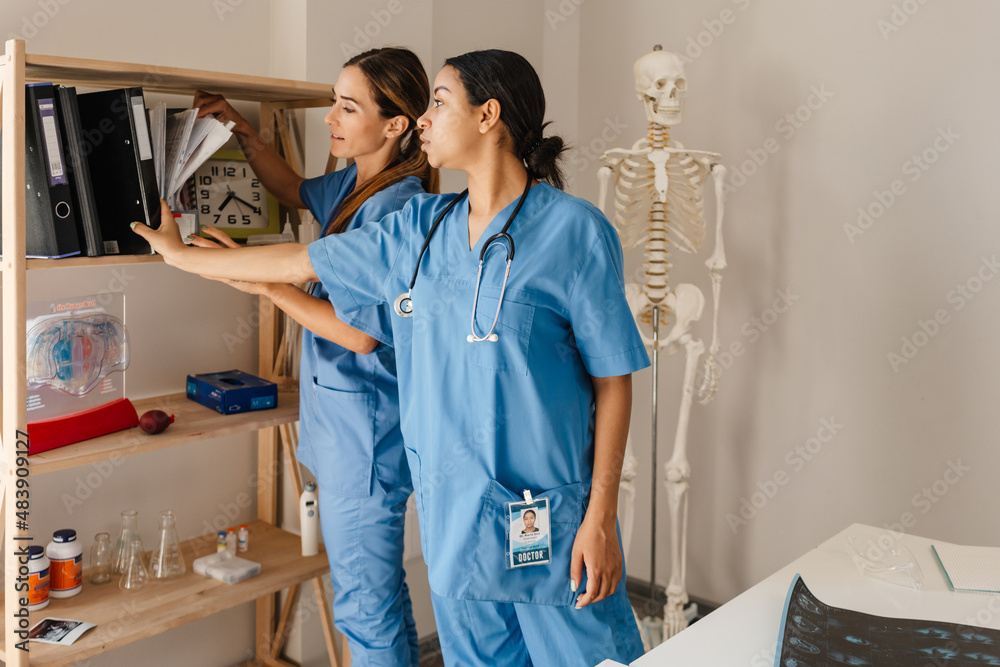 Fototapeta premium Multiracial women doctors talking while working with papers in office