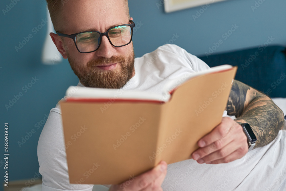 Positive man reading book at home - obrazy, fototapety, plakaty 