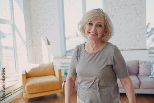 Elderly caucasian old aged 60 year old granny portrait gray haired positive smiling stand indoors