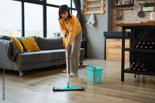 Fotografi Full length portrait of young Asian woman mopping floors while cleaning cozy apa