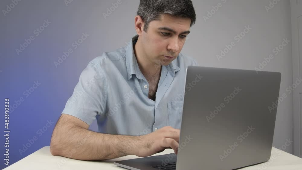 A man carefully prints on a laptop reads what he wrote