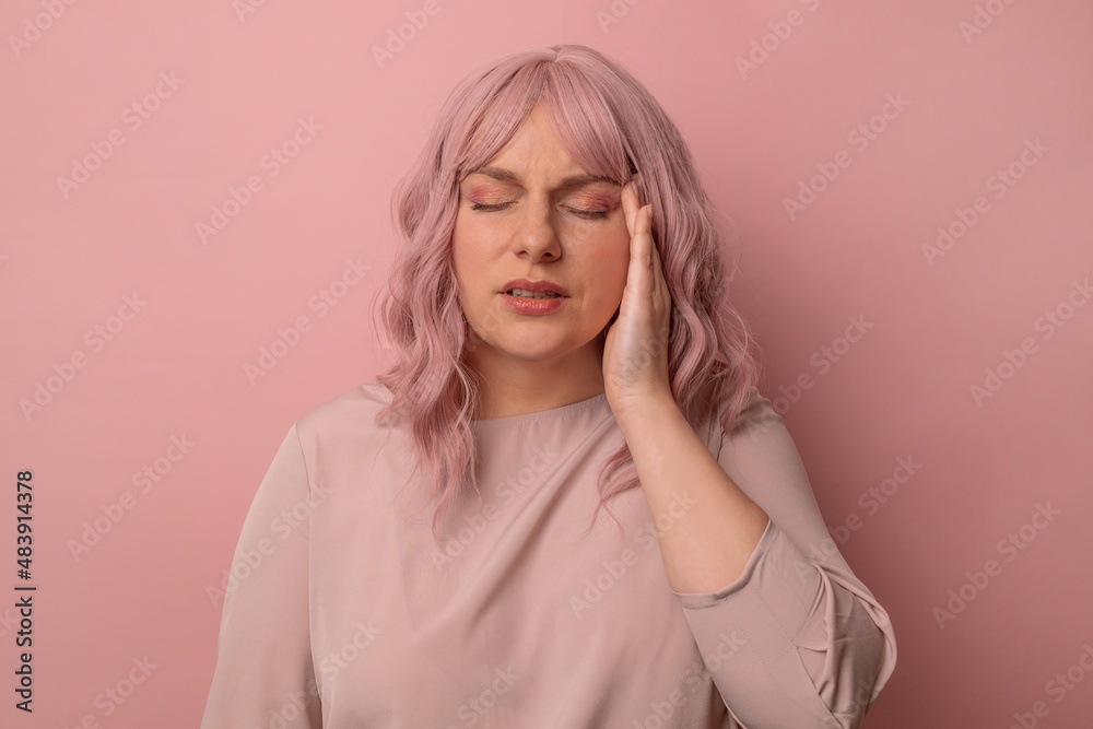 Handsome pink hair 30s woman standing with hand on head for pain in head because stress over isolated pink background. Suffering migraine. Health and stress concept Handsome pink hair 30s woman standing with hand on head for pain in head because stress over isolated pink background. Suffering migraine. Health and stress concept