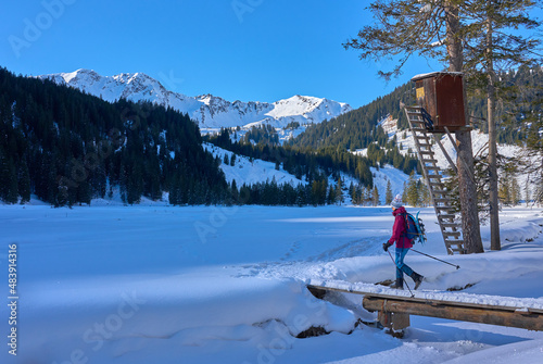  nice senior woman snowshoeing in the snowy landscape of Kleinwalsertal in Vorarlberg, Austria