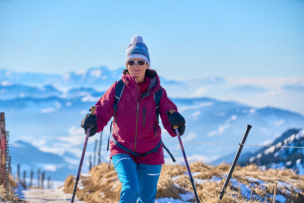  nice senior woman snowshoeing on the Nagelfluh chain above a sea of fog over Bregenz Wald mountains, Hochgrat, Steibis,Bavarian alps, Germany