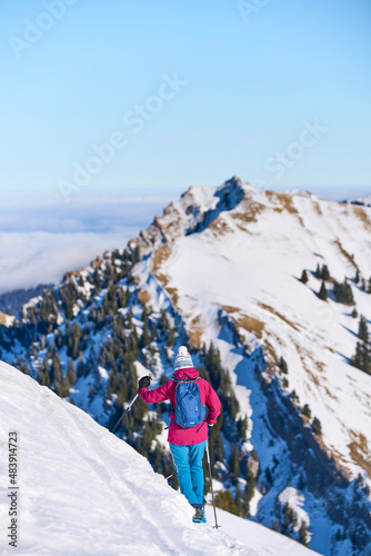 nice senior woman snowshoeing on the Nagelfluh mountain chain above a sea of fog over Bregenz Wald mountains, Hochgrat, Steibis,Bavarian alps, Germany 