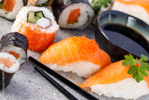 Sushi with salmon and caviar closeup. Sushi set with soy sauce, chopsticks and parsley on stone