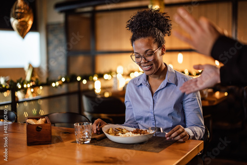 Happy African-American woman  preparing to take a bite of her food  talking to the waiter.