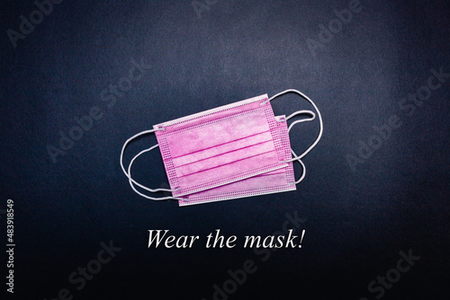 Two pink face masks in the center on a black background with "wear the mask" inscription