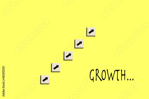 Professional growth concept with wooden cubes with arrows and writing "growth" on yellow background