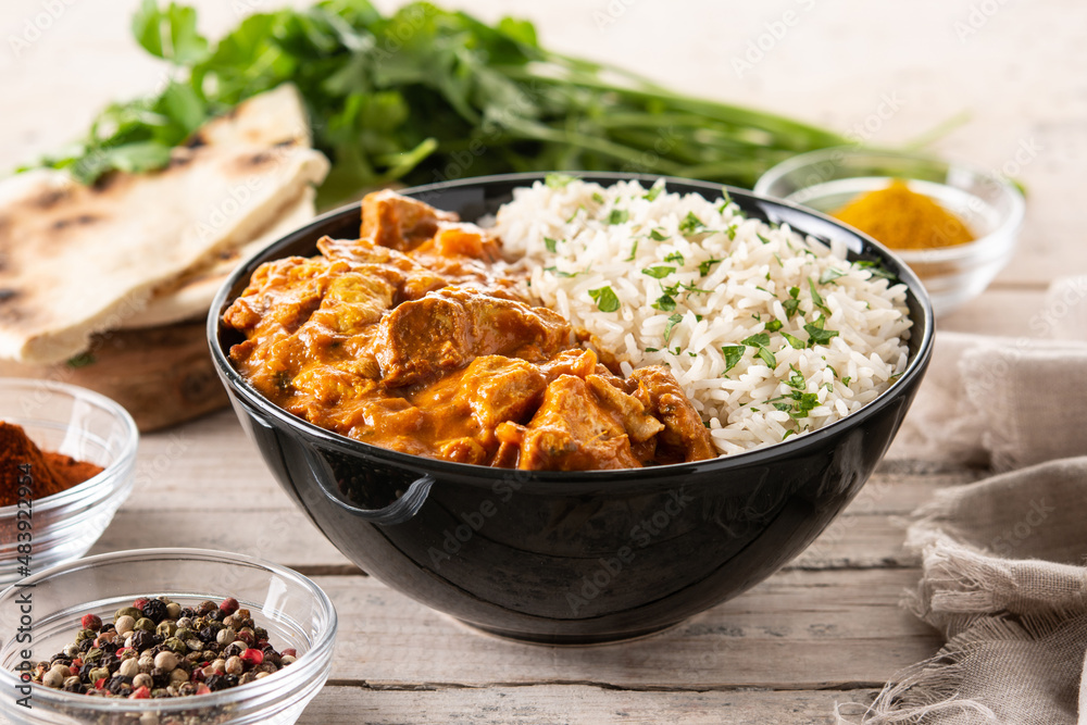 Indian butter chicken in black bowl on wooden table Indian butter chicken in black bowl on wooden table