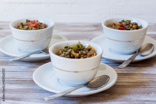 Fotografija Lentil and escarole soup served in white cups on white wooden background