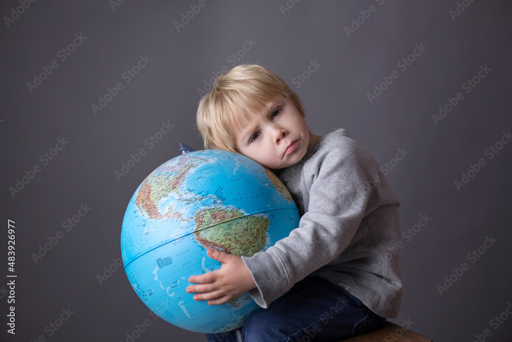 Cute toddler child, boy, hugging big globe, isolated image Cute toddler child, boy, hugging big globe, isolated image
