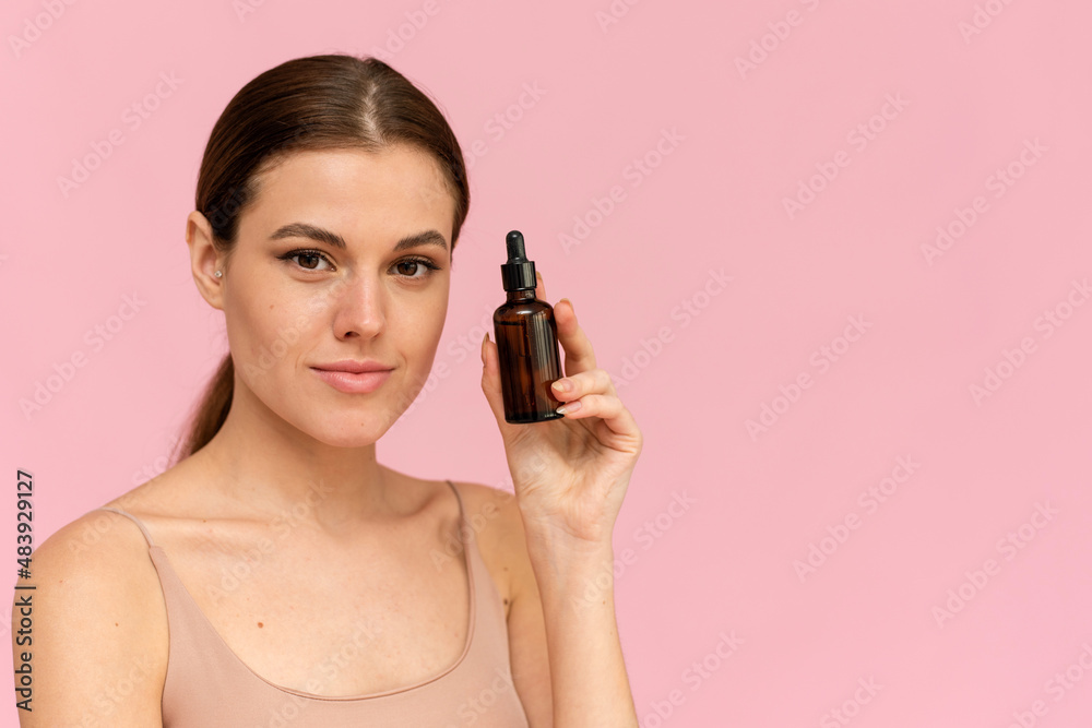 Fototapeta premium A beautiful young woman moisturizes her skin with a serum. Caring for the skin. Essential Oil For Anti-Aging Therapy