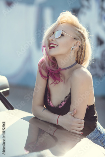 Portrait of young woman with piercings and tattoos against graffiti wall.