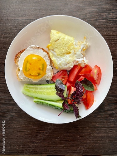 large vertical photo. breakfast. healthy food. scrambled eggs with fresh vegetables and basil on a white plate. top view close-up.
