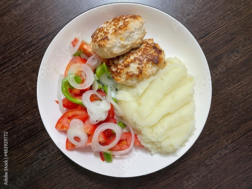 large horizontally photo. fried chicken cutlets with mashed potatoes and fresh vegetables on a white plate. Healthy food. ECO. Home serving.