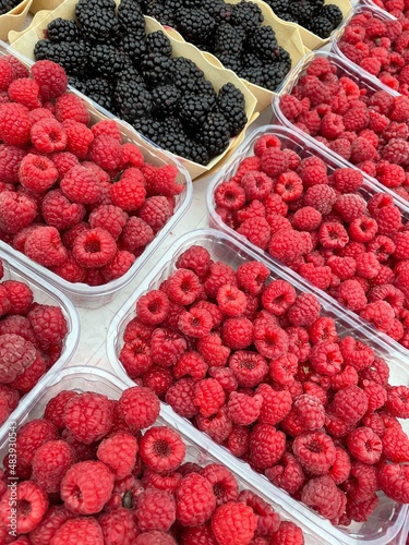 large vertical photo. raspberries and blackberries in plastic containers. containers with berries standing diagonally. photo above. healthy natural berries. eco.