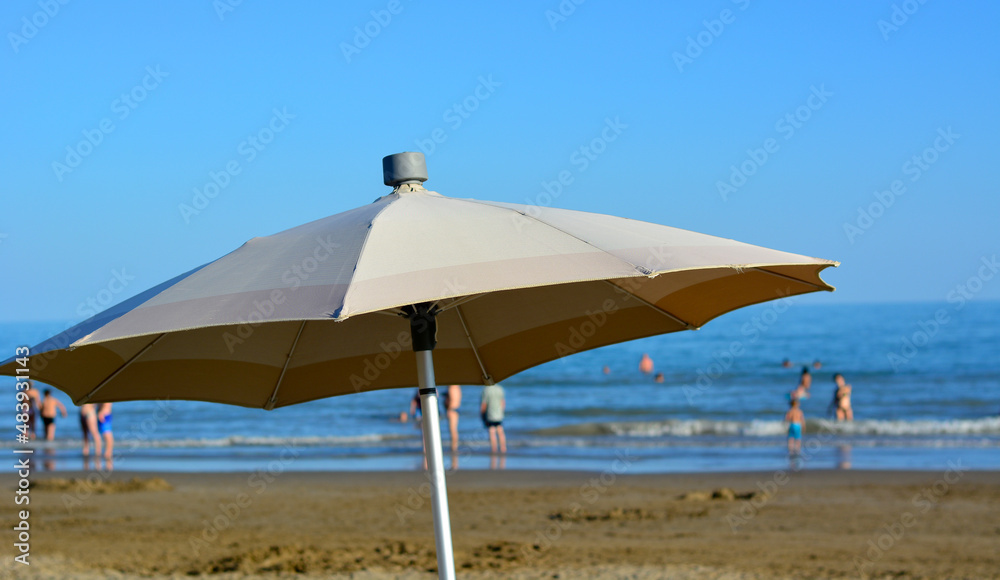 an umbrella in front of the waves of the sea and the blue sky