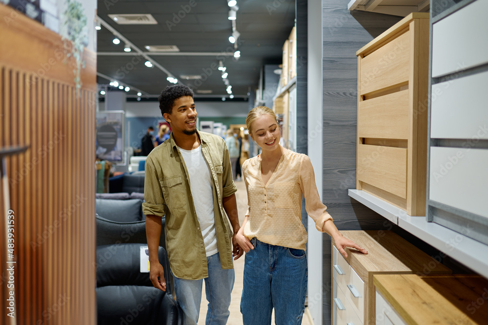 Couple walking along shopping arcade with furniture