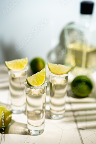 Mexican Gold Tequila with lime and salt on white background with shadows and copyspace.